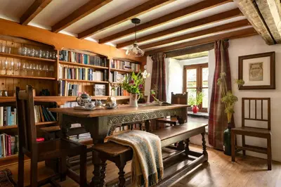 a library with a table and chairs and bookshelves at Gwanas Fawr in Dolgellau