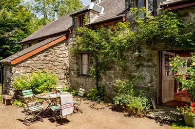 a table and chairs in front of a stone house at Gwanas Fawr in Dolgellau