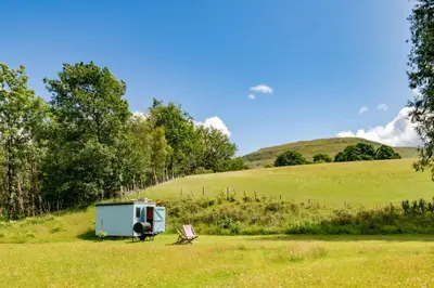 a blue shed and a chair in a field at Gwanas Fawr in Dolgellau