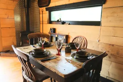 a wooden table with plates and glasses on it at Woodcutters' Cabin Authentic Log Cabin Talybont Aberystwyth SY245DW in Aberystwyth