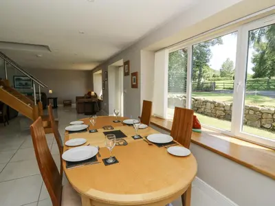 a dining room with a table with chairs and windows at Little Penrhosgoch Barn in Llandrindod Wells