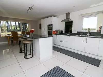 a white kitchen with white cabinets and a table at Little Penrhosgoch Barn in Llandrindod Wells