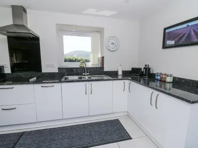a kitchen with white cabinets and a clock on the wall at Little Penrhosgoch Barn in Llandrindod Wells