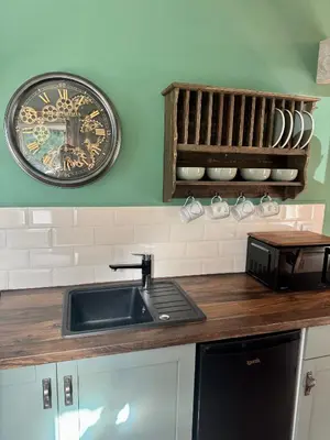 a kitchen with a sink and a clock on the wall at The Robin, Arrowwood Self Catering in Kington