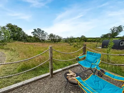 a blue chair and a pair of shoes next to a fence at The Owl Pod - Uk50070 in Welshpool