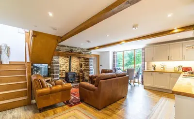 a kitchen and living room with leather chairs and a fireplace at Y Pandy in Pennal