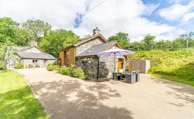 a stone cottage with an umbrella in front of it at Y Pandy in Pennal