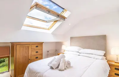 a bedroom with a large white bed with a skylight at Y Pandy in Pennal