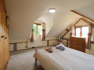 a bedroom with a large bed and a window at Callow Cottage in Craven Arms