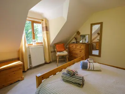 a bedroom with a bed and a dresser and a mirror at Callow Cottage in Craven Arms