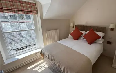 a bedroom with a bed with red pillows and a window at Community Owned Gwesty Owain Glyndwr Hotel in Corwen