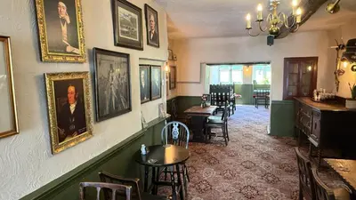 a dining room with portraits on the wall and chairs at Community Owned Gwesty Owain Glyndwr Hotel in Corwen