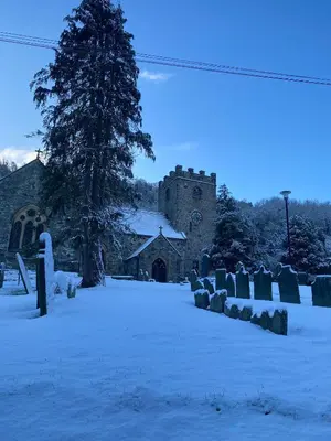 a church in the snow with a tree at Community Owned Gwesty Owain Glyndwr Hotel in Corwen