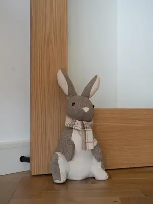 a stuffed rabbit wearing a scarf sitting on the floor at Modern Bungalow Views of Pen y Fan in Brecon