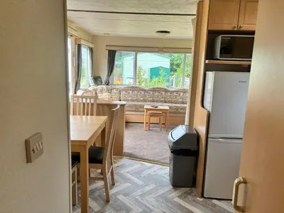 a kitchen and living room with a table and a refrigerator at Cadwgan Caravan No2 in Barmouth