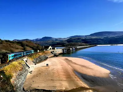a train on a beach next to the water at Cadwgan Caravan No2 in Barmouth