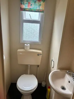 a bathroom with a toilet and a sink and a window at Cadwgan Caravan No2 in Barmouth