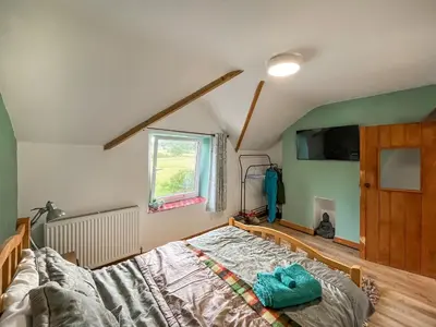 a bedroom with a bed and a window at Swan Cottage in Carrog