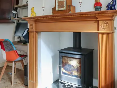 a woodburning stove in a living room with a chair at Crescent Cottage in Newtown