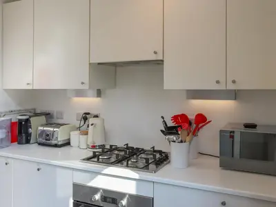 a kitchen with white cabinets and a stove top oven at Crescent Cottage in Newtown