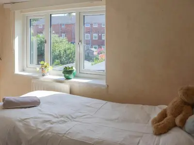 a teddy bear sitting on a bed in front of a window at Crescent Cottage in Newtown