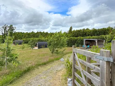 a fence on a dirt road next to a field at The Sheep Pod - Uk50074 in Welshpool