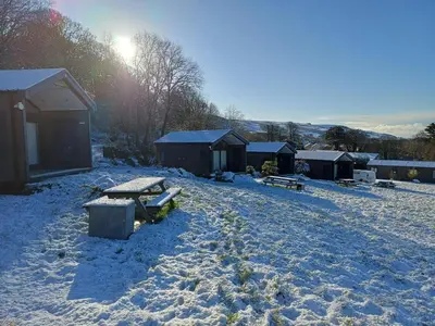 a snow covered yard with a picnic table and buildings at CABIN 8 Pet friendly Family glamping Seaview in Llwyngwril