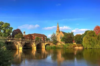 a bridge over a river with a building and a church at Honey Bee Cottage Tiny House Welshpool in Welshpool