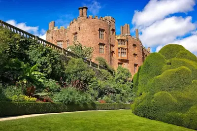 an old castle with a garden in front of it at Honey Bee Cottage Tiny House Welshpool in Welshpool
