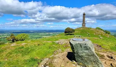 a lighthouse on top of a grassy hill at Honey Bee Cottage Tiny House Welshpool in Welshpool