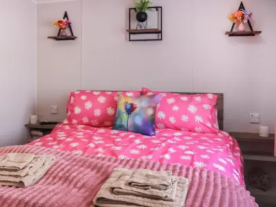 a bedroom with a pink bed with towels on it at The Laughing Seagull - Uk50213 in Aberystwyth
