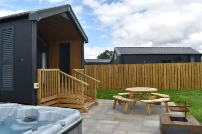 a tiny house with a hot tub and a table and bench at Daverneithon 3 in Rhayader
