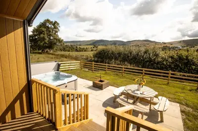 a deck with a hot tub and a table at Daverneithon 1 in Rhayader