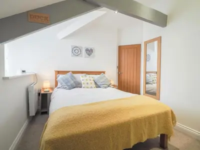 a bedroom with a large bed with a yellow blanket at Sailhouse Loft New Quay in New Quay