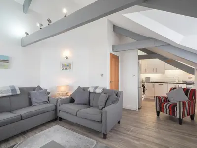 a living room with two couches and a kitchen at Sailhouse Loft New Quay in New Quay