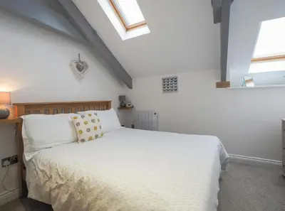 a bedroom with a white bed and two windows at Sailhouse Loft New Quay in New Quay