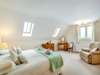a bedroom with a bed and a chair and windows at Orchard Barn in Llandrindod Wells