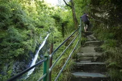 a man walking up some stairs next to a waterfall at 4 Bed in Talybont oc-y32384 in Talybont