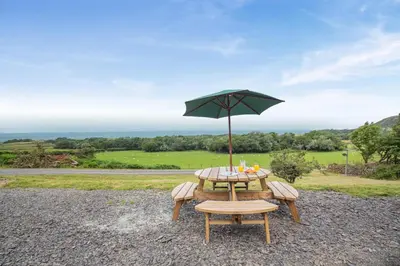 a picnic table with an umbrella and a chair at 3 Bed in Tywyn oc-b32570 in Llangelynin
