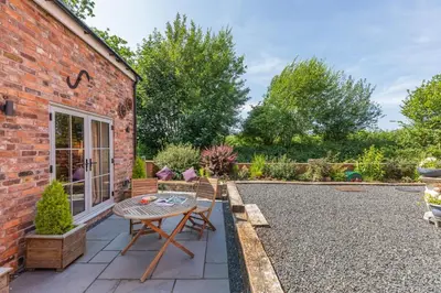 a patio with a table and chairs and a brick building at 2 Bed in Carreghofa oc-t32530 in Llanymynech