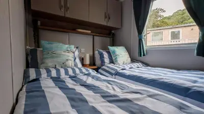 two beds in a room with a window at The Ocean Nook in New Quay