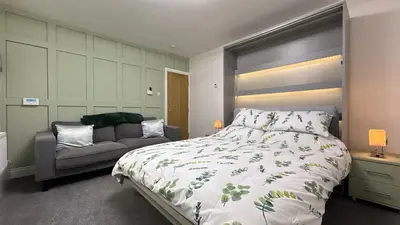 a bedroom with a large bed and a couch at Barmouth Beach Ground Floor Studio in Barmouth