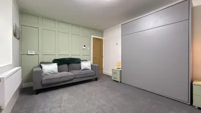 a living room with a couch and a wall at Barmouth Beach Ground Floor Studio in Barmouth