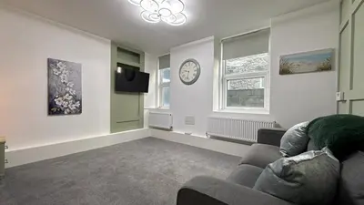 a living room with a couch and a clock on the wall at Barmouth Beach Ground Floor Studio in Barmouth