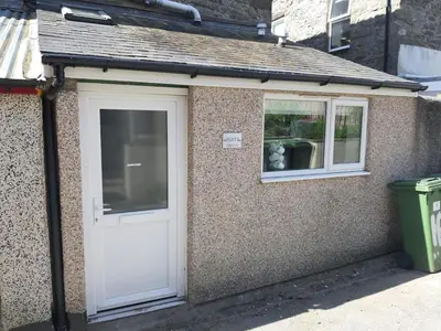 a small building with a white door and a window at Barmouth Beach Ground Floor Studio in Barmouth