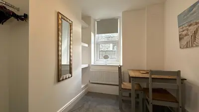 a room with a table and a mirror and a window at Barmouth Beach Ground Floor Studio in Barmouth