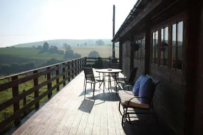 a porch with chairs and a table on a building at Perfect getaway Cabin Haf with Hot Tub in Llanrhaeadr-ym-Mochnant