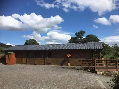 a large wooden barn with a fence at Perfect getaway Cabin Haf with Hot Tub in Llanrhaeadr-ym-Mochnant