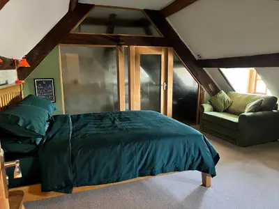 a bedroom with a large bed and a couch at Rooftops Loft in Hay-on-Wye