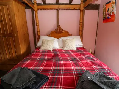 a bedroom with a bed with a red plaid blanket at The Little Laura Ashley House in Machynlleth